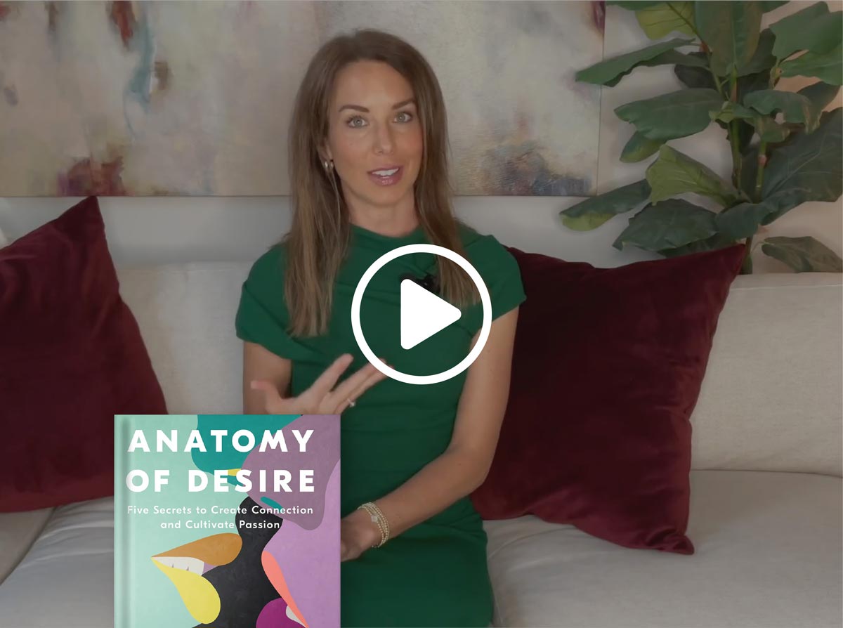 Woman holding a book titled 'Anatomy of Desire' on a couch with a play button overlay.