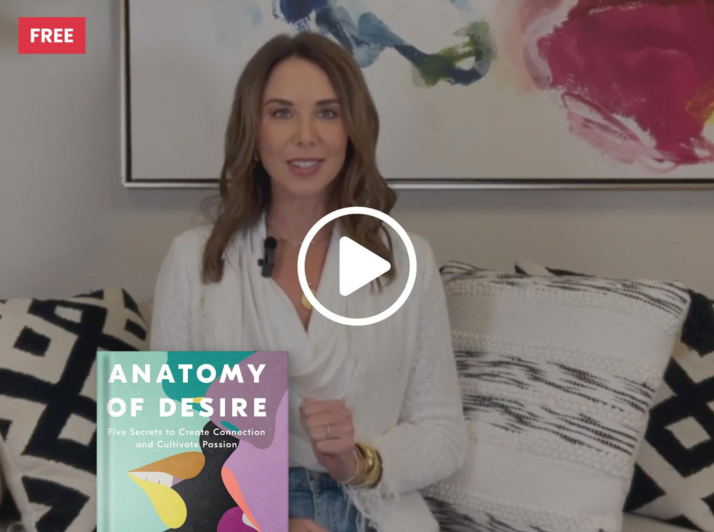 Woman holding a book titled 'Anatomy of Desire' in a living room setting with a play button overlay.