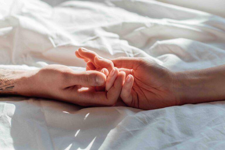 16 Hands-Free Dildos and Vibrators That'll Totally Change Up Your Sex Game - Couple holding hands in bed
